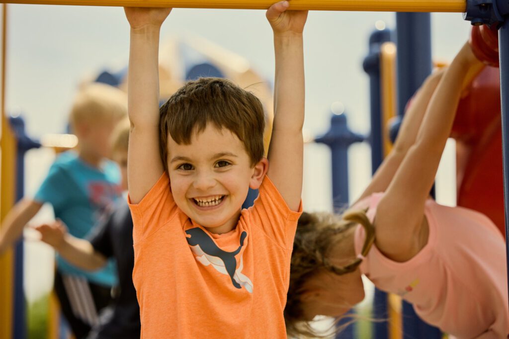 Early Childhood student smiles as he conquers the monkey-bars outside Abiding Savior Lutheran School.