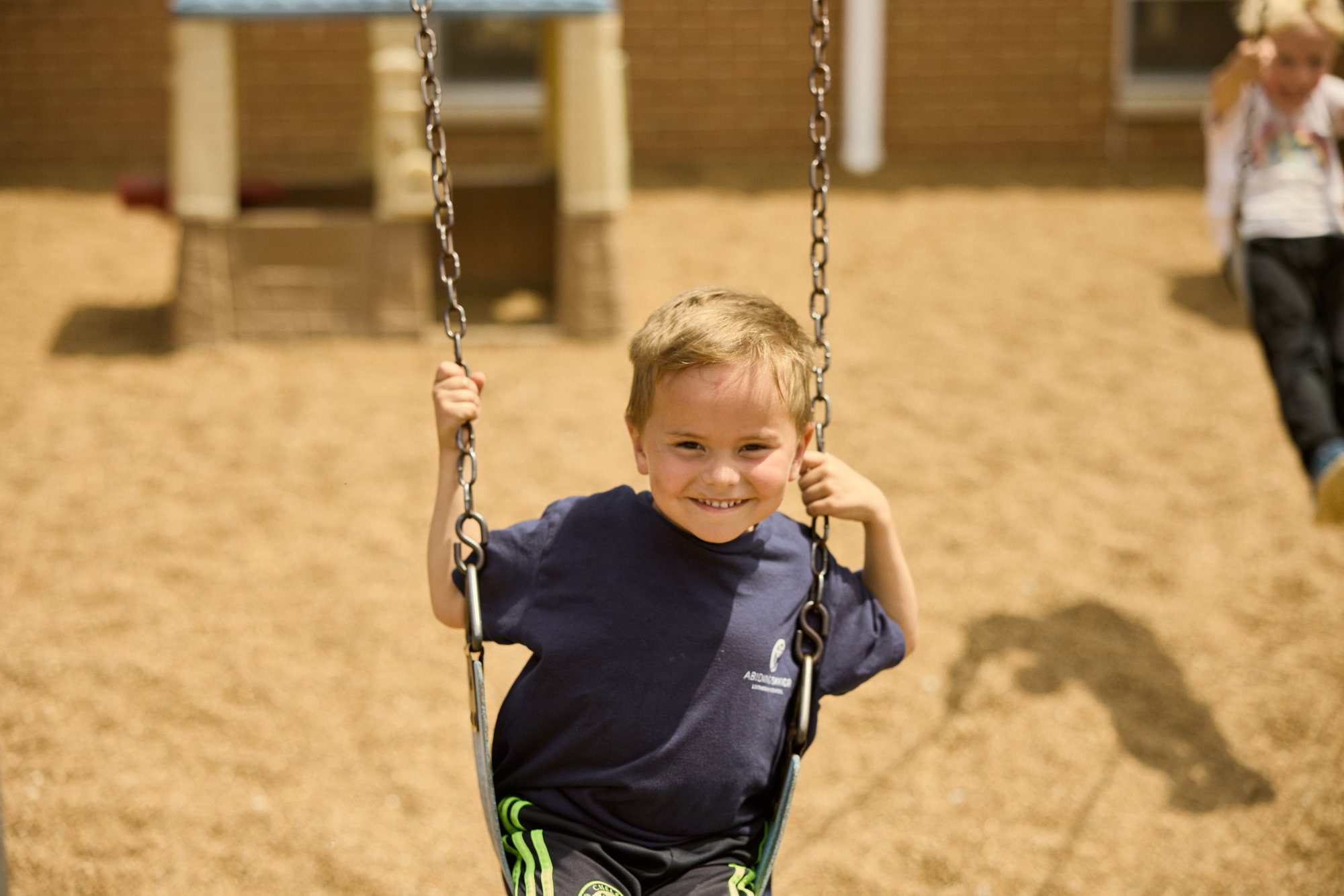 Early childhood boy smiles on the swing.