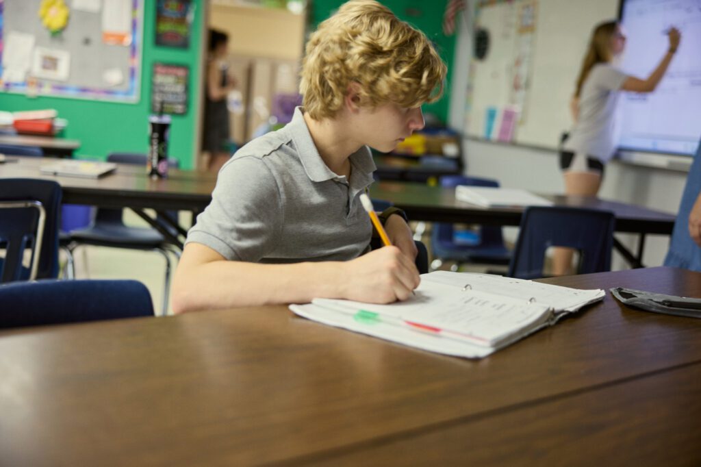 Middle school student writes at his desk.