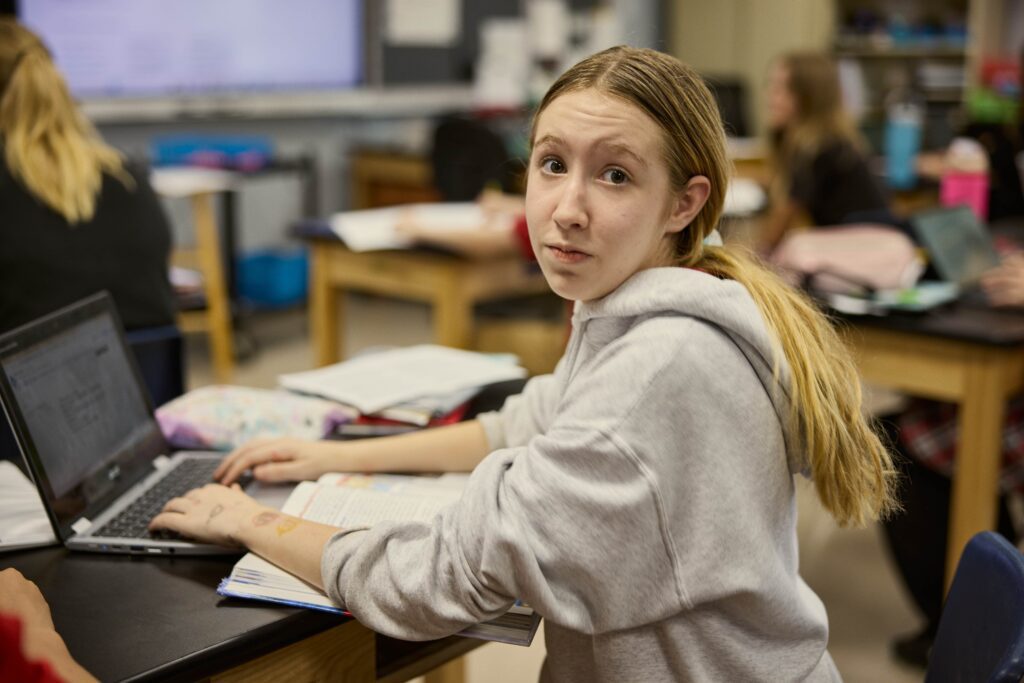 Middle school girl looks at camera briefly while working at her desk.