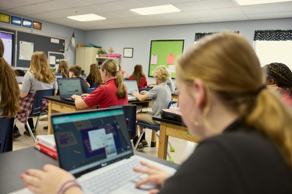 Middle school students work at their desks in full classroom.