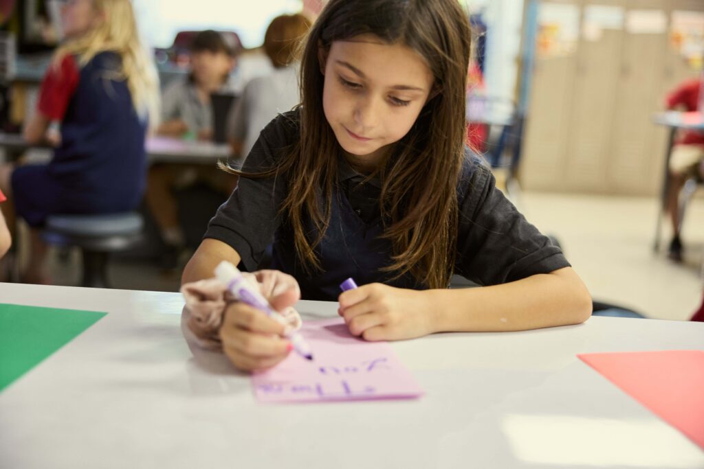 Elementary age girl creates Valentines card with markers.