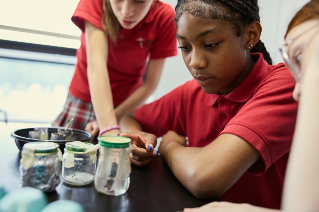 Middle school students observe plant life growing in test containers in a school lab.