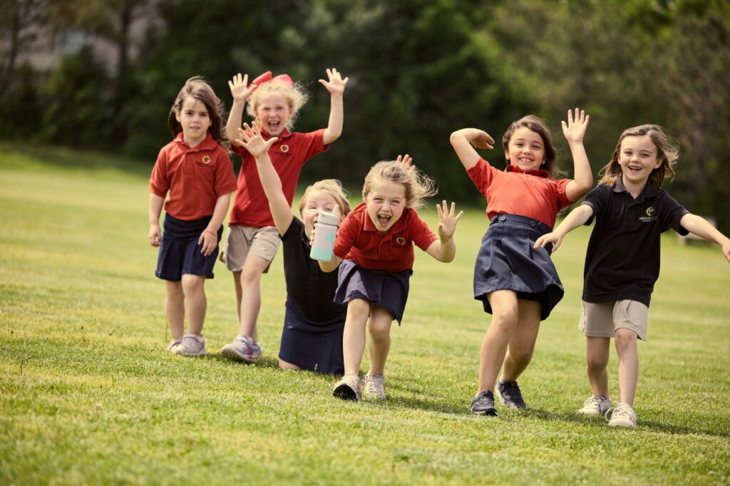 Group of girls run towards the camera on school field.