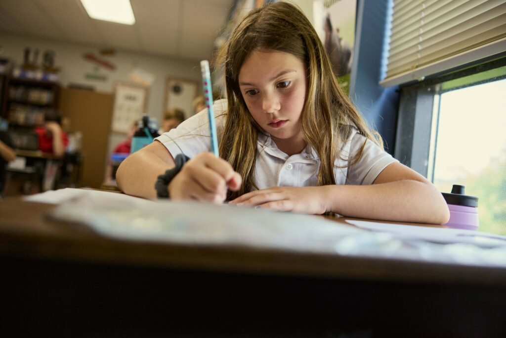 Student writes down notes with a pencil and paper in her Elementary classroom.