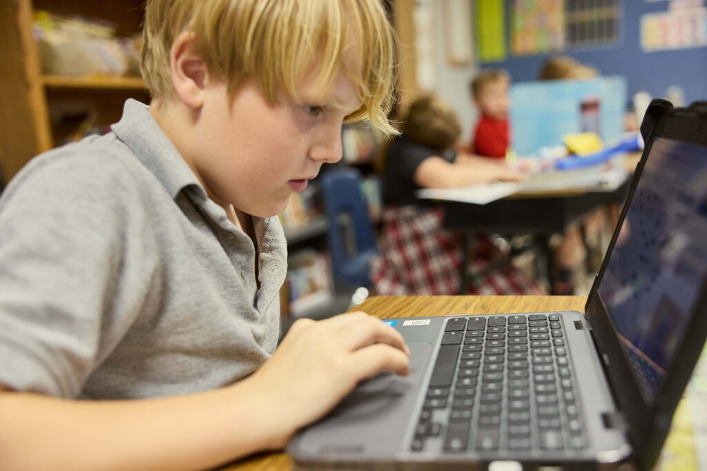 Elementary student works on his assignment with a laptop in class.