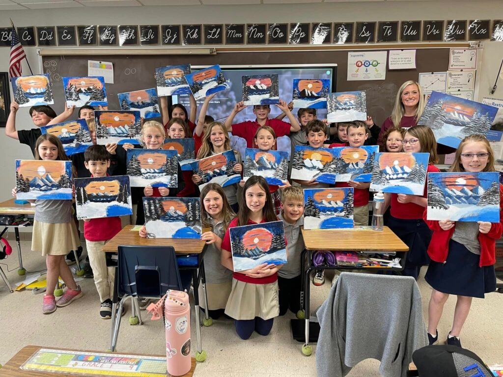 Art class students all pose for a picture where they all show the art they have made in school.