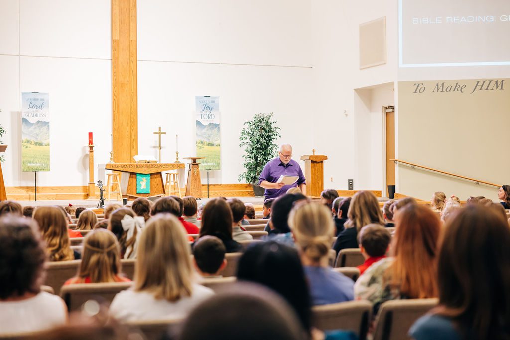 A staff member from Abiding Savior Lutheran School leads Faith Formation in front of a classroom full of students.