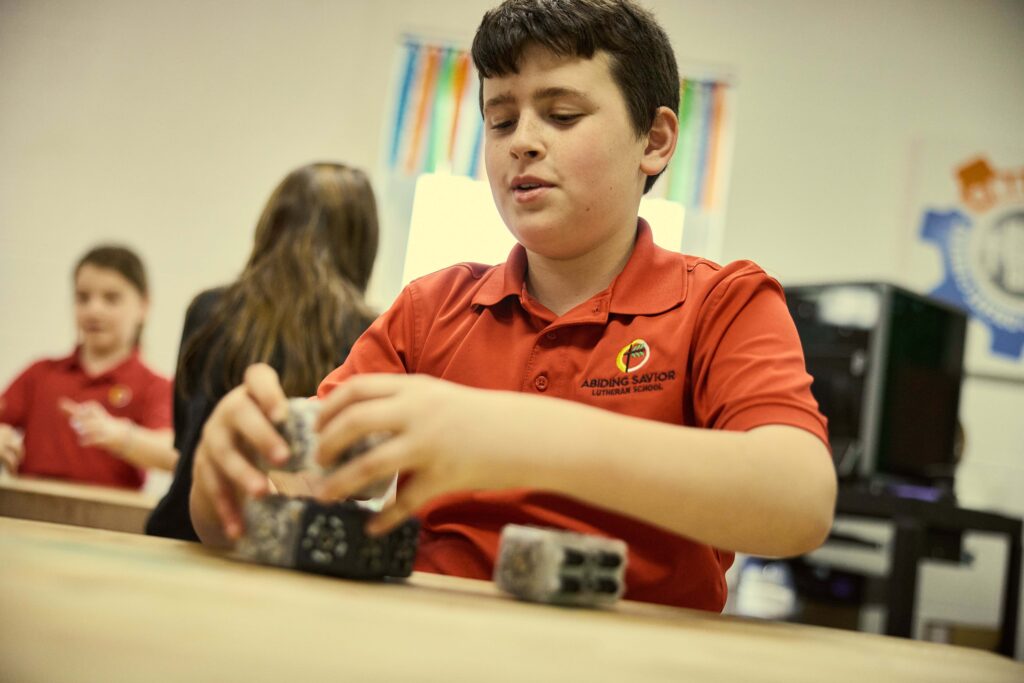 Middle school students use math manipulatives at the table.